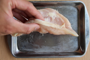 鶏むね肉をまな板の上におき、めんぼうで厚さが約2cm幅の均等になるまでたたく。