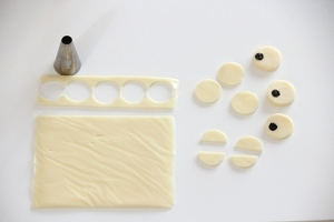 スライスチーズは小さな丸型（ここでは搾り出し口の後ろを使っています）で型抜き、“目”になるものは丸く切った海苔を貼り、“ウロコ”になるものは半分に切る。抜いた残りのチーズも飾りに使えます。