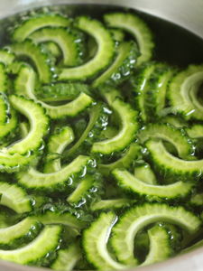 ゴーヤは縦半分に切り、スプーンでわたをしっかり取り除く。3〜5mm幅の半月切りにし、濃いめの塩水に約10分浸したらザルにあけ、キッチンペーパーで水分をふきとる。付け添えの野菜は準備しておく。