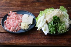 白菜の葉は5㎝角に、芯は削ぎ切りにする。水菜は5㎝幅に、長ネギは斜め切り、えのきは石付きを切ってほぐす。生姜は千切りにする。豆腐は4等分に切る。