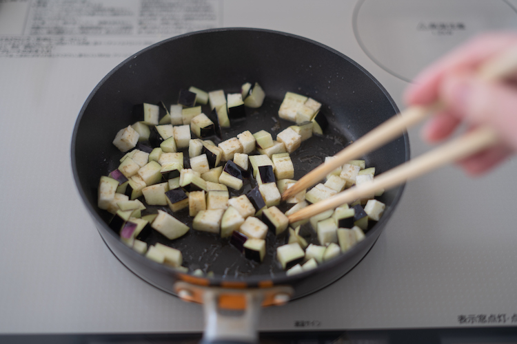 フライパンを中火で熱して2/3量のごま油を加え、水気をよく切ったなすを加えて炒める。全体にしんなりとしてきたら残りのごま油を入れ、豚肉とピーマンを加えて炒める。