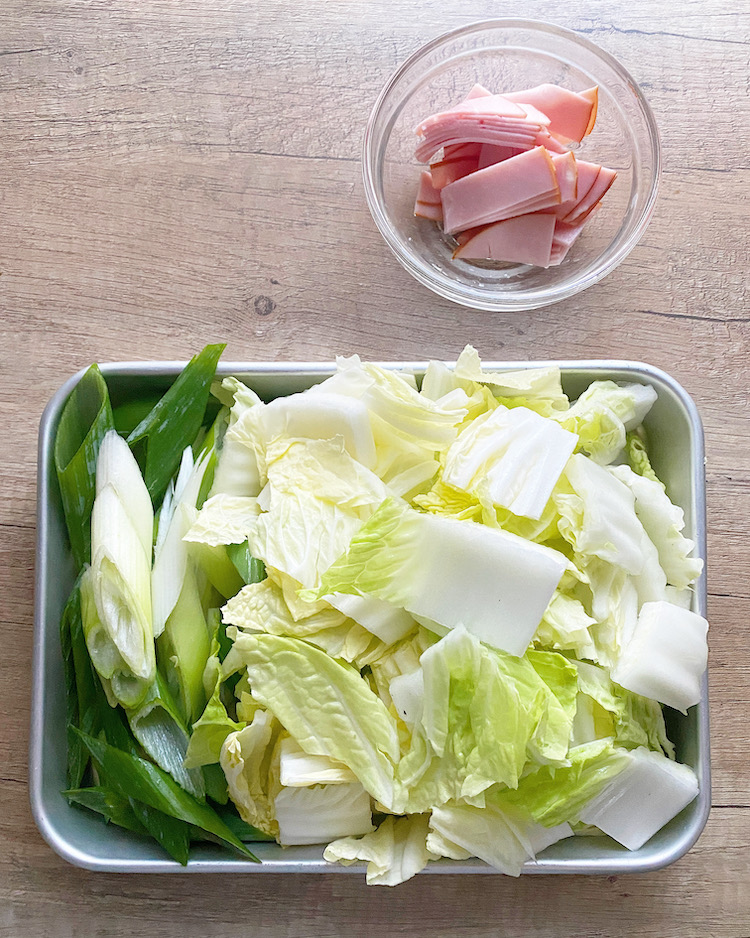 白菜は食べやすい大きさのざく切りにする。長ねぎは斜め切りにする。ハムは半分に切ってから1cm幅程度に切る。